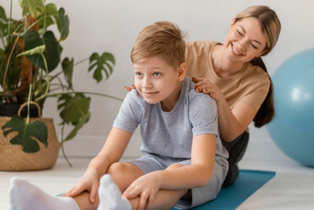 mujer ayuda a niño con ejercicios fisioterapia